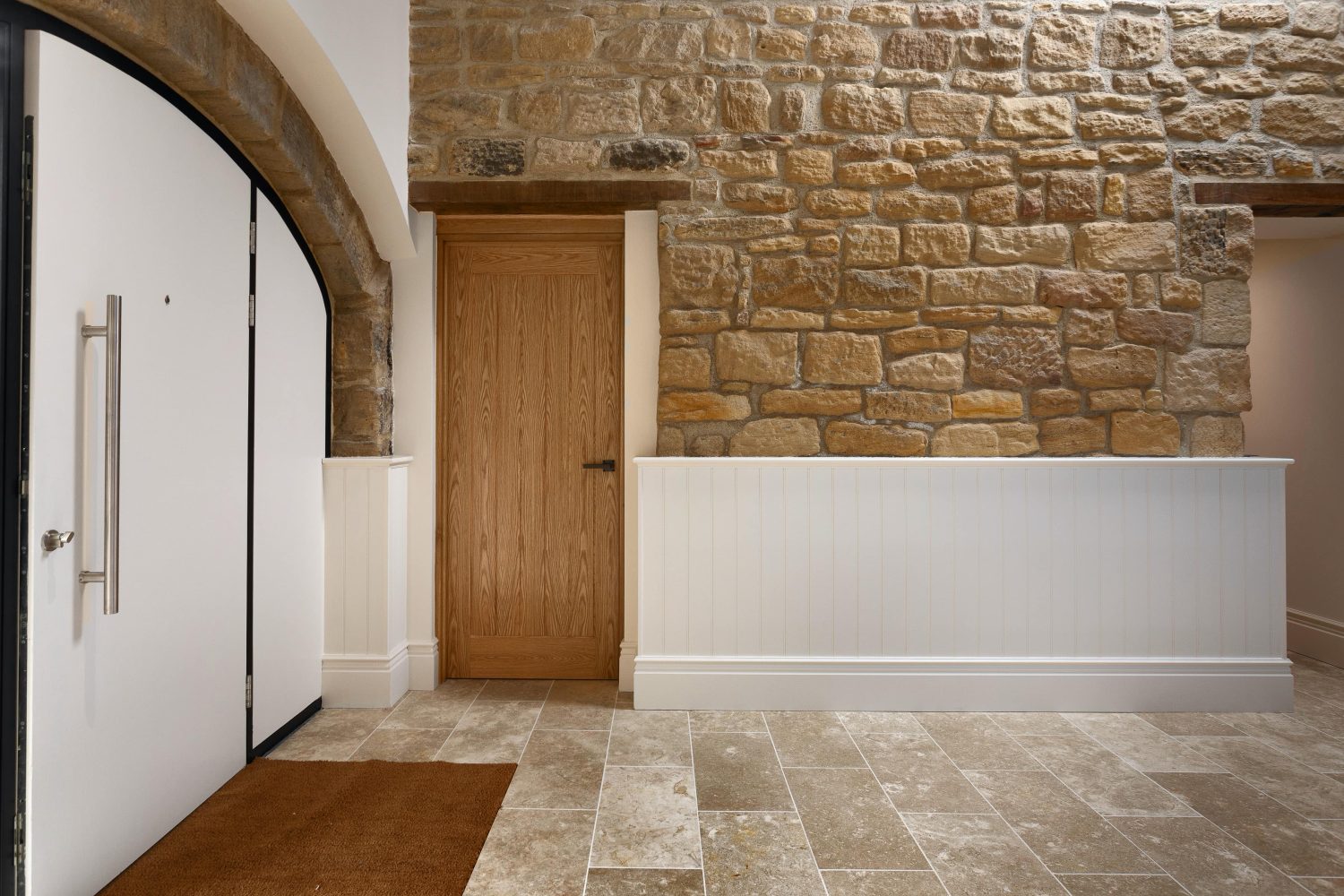 Entryway with arched door and wooden door in exposed stone wall