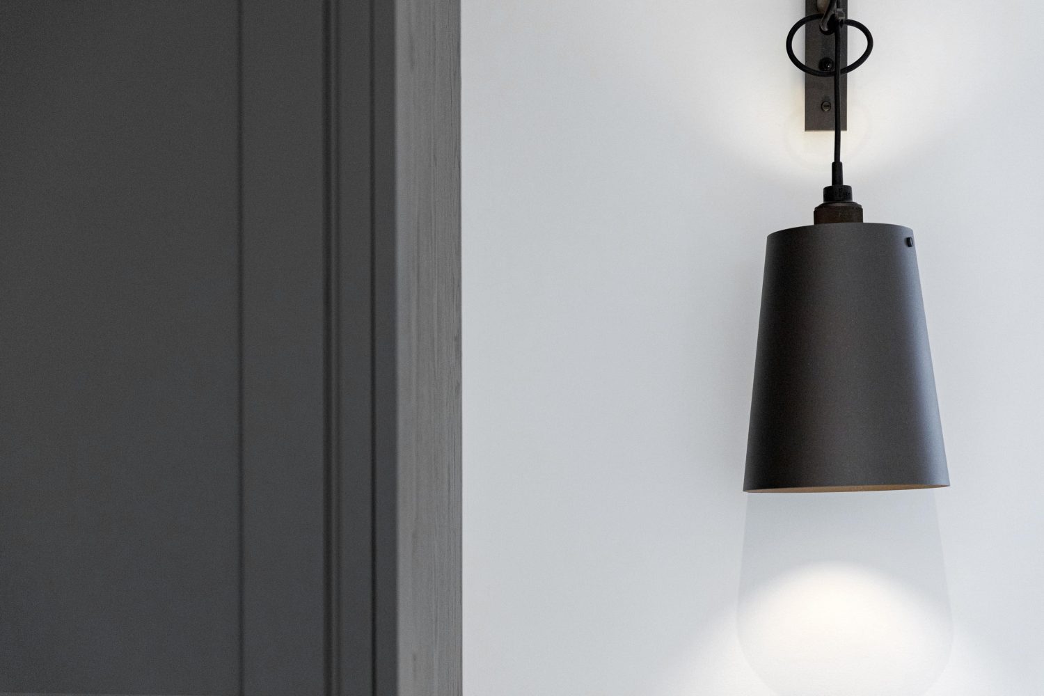 black pendant wall lamp on white wall beside dark grey cabinet