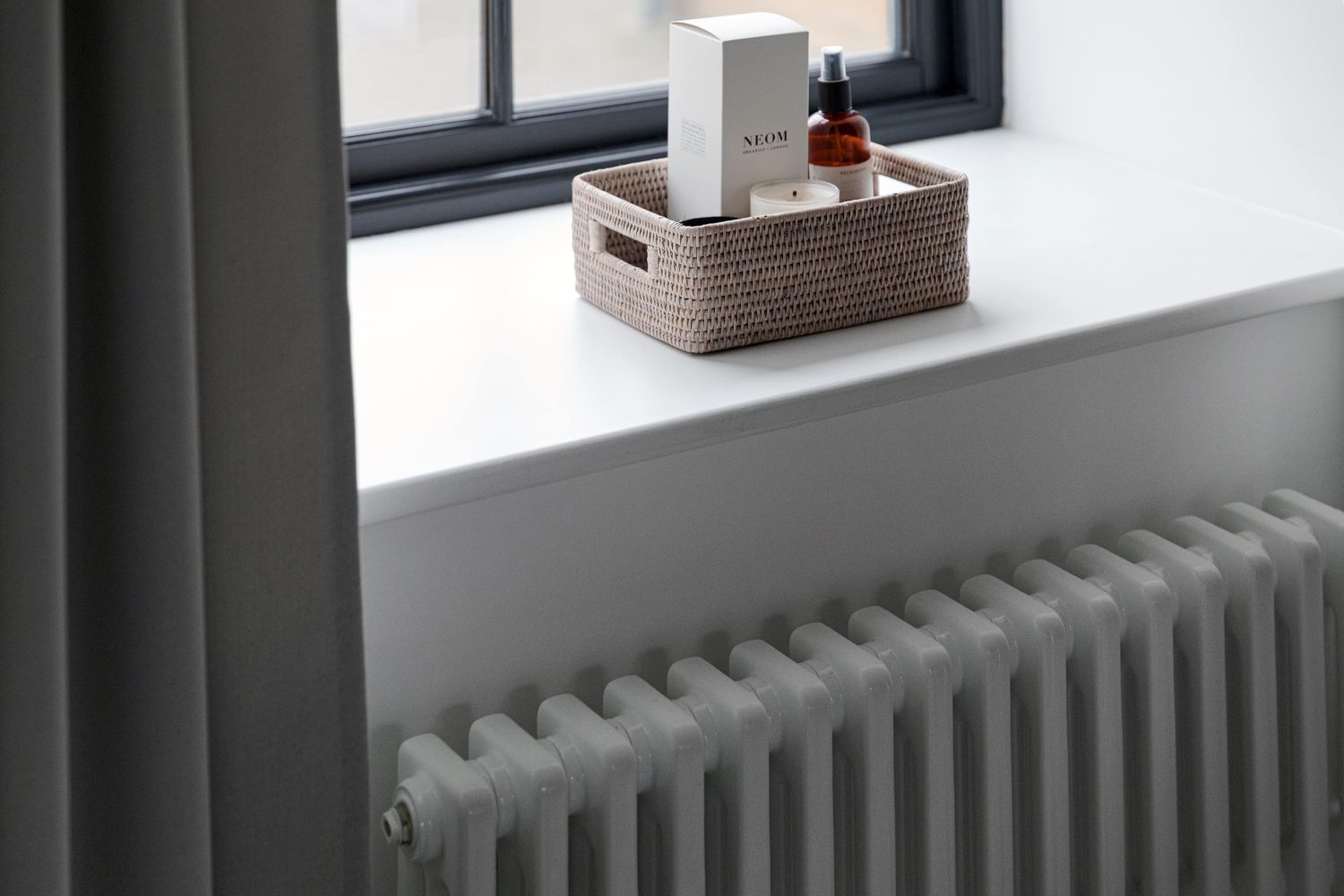 Large white windowsill with wicker basket on top and white radiator beneath