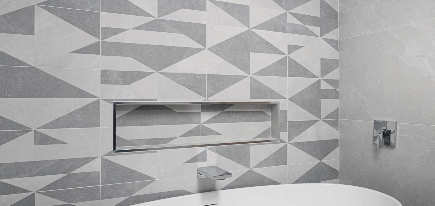 Grey and white geometric patterned wall with shower niche and silver taps