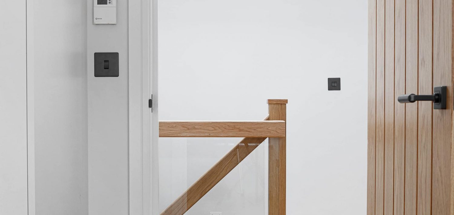 View through white doorway with wooden door to wooden stair banister