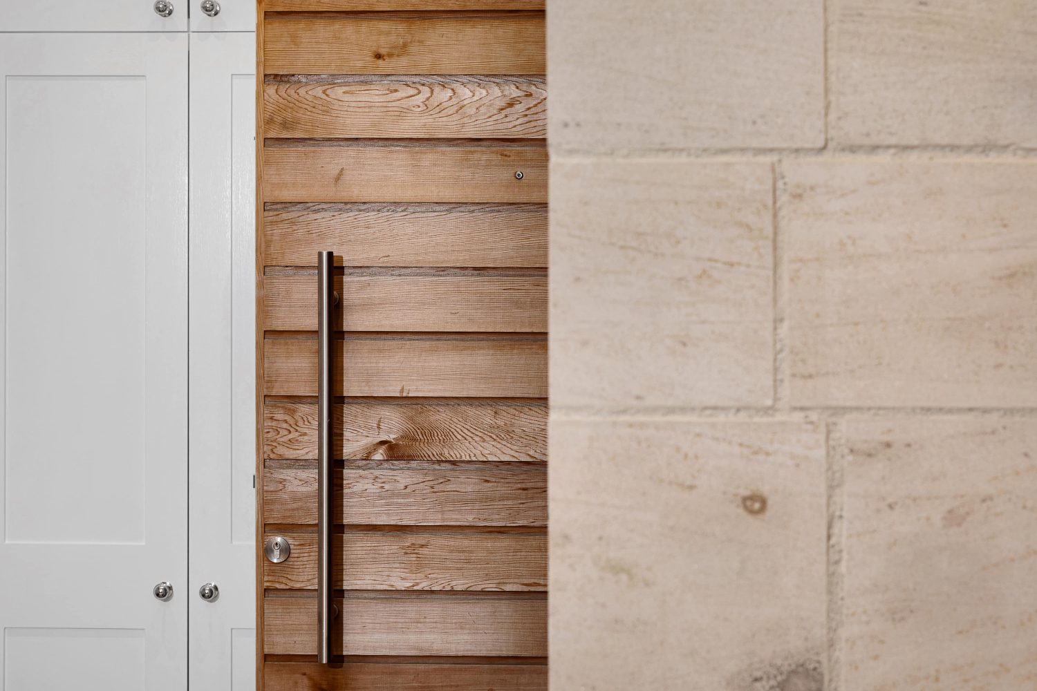Trio of white painted doors next to wooden panelled door and exposed stone wall