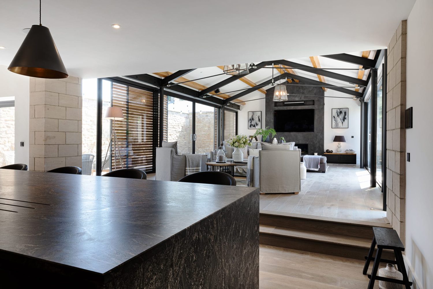 View of living room with grey sofas behind dark grey marble kitchen island