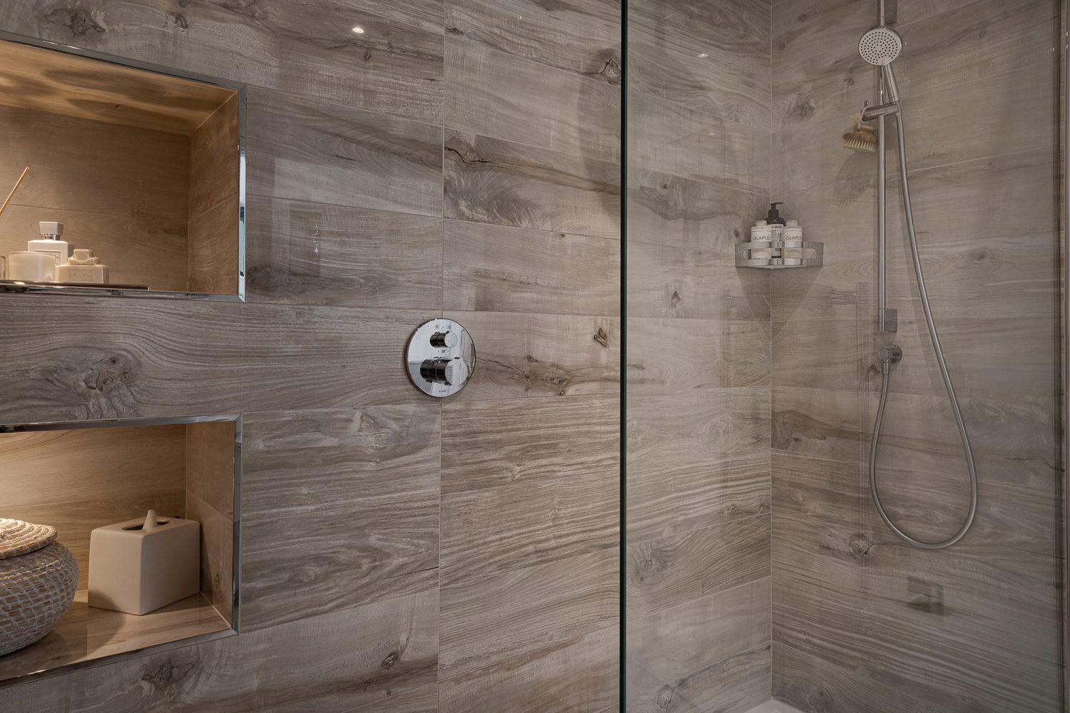 Shower with wooden style tiled walls and chrome taps and two large shower niches