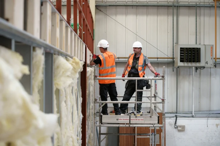 Two construction workers on an elevated platform performing works