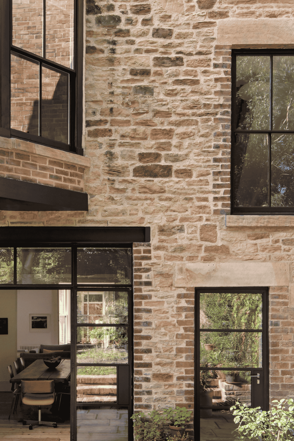 Exterior wall of house with exposed brick and stone walls and Crittall style doors and windows