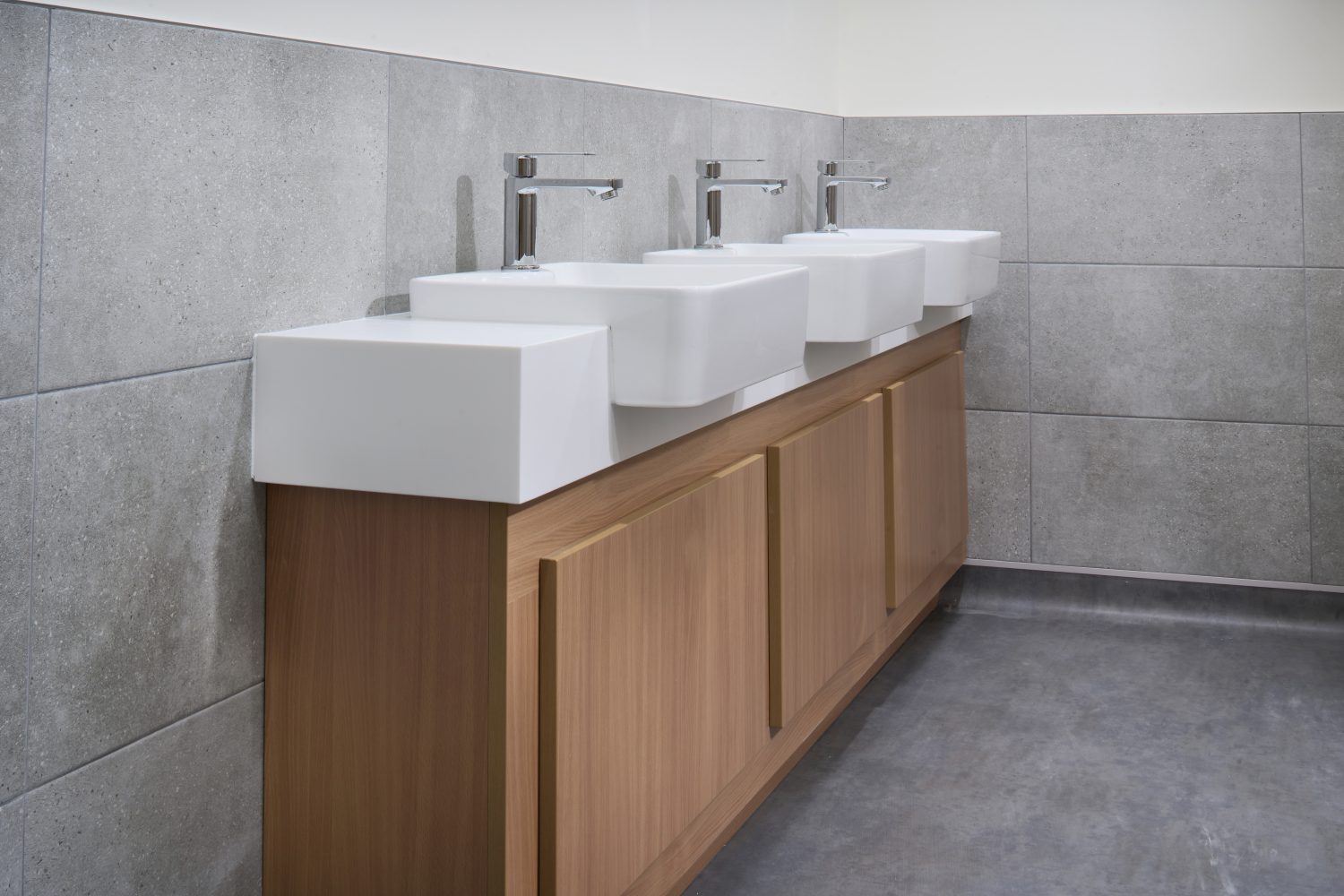 Bathroom sinks unit white white sinks on top of wooden unit with light grey tiles surrounding