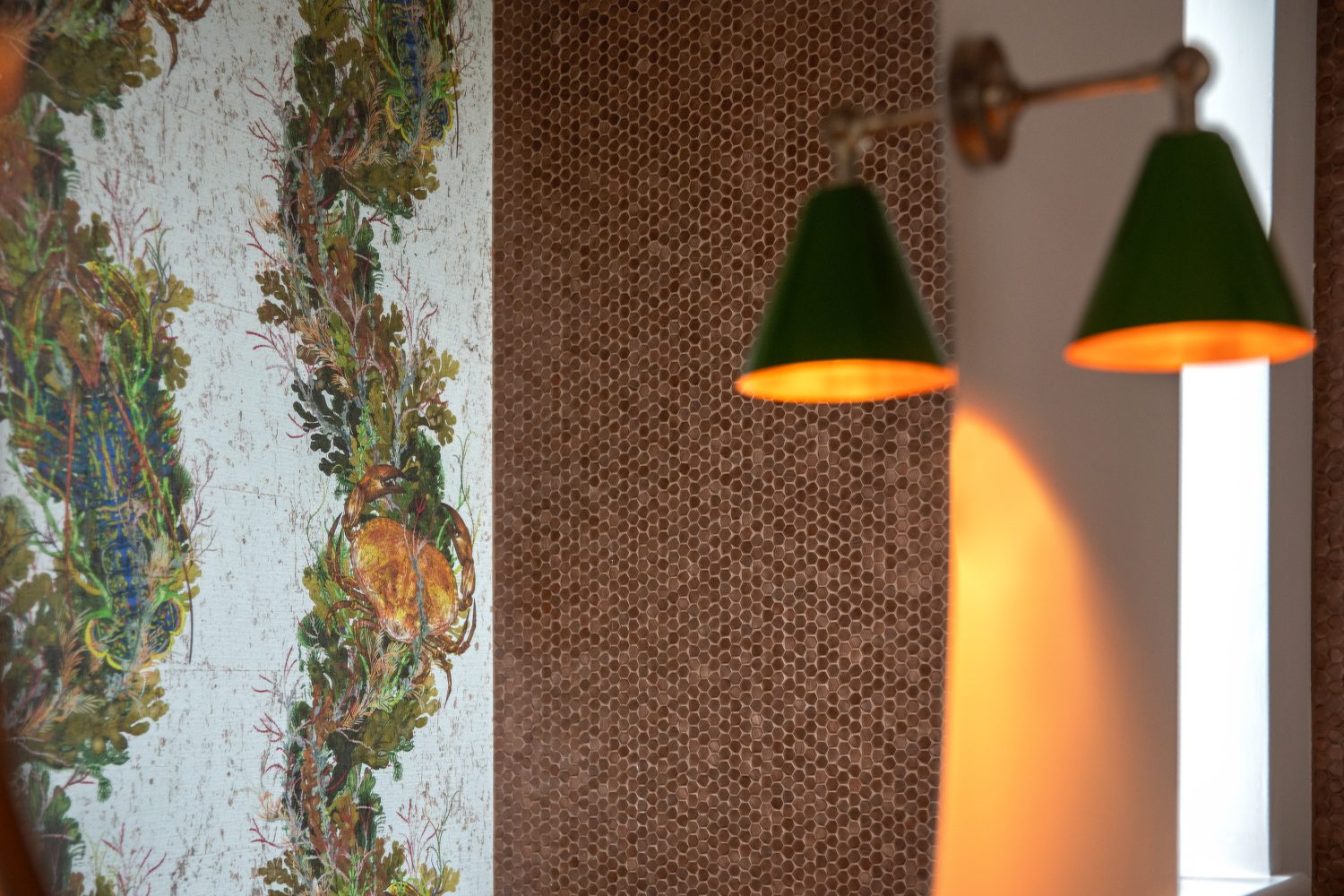 Copper tiled wall next to wall with nature print wallpaper