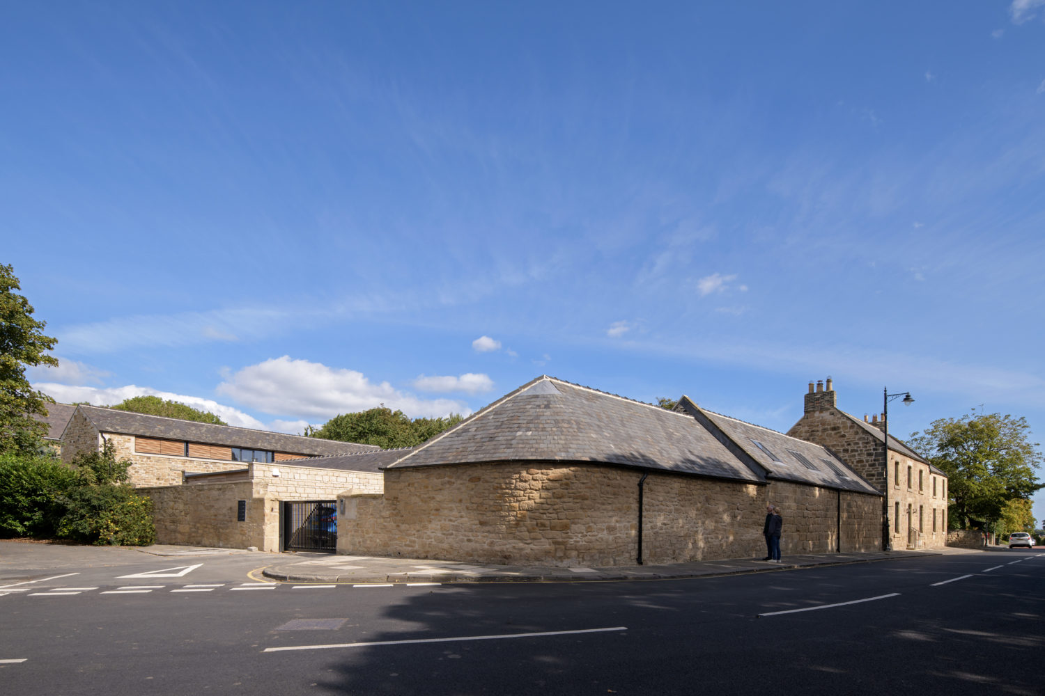 View across road of a stone built house curving around a corner
