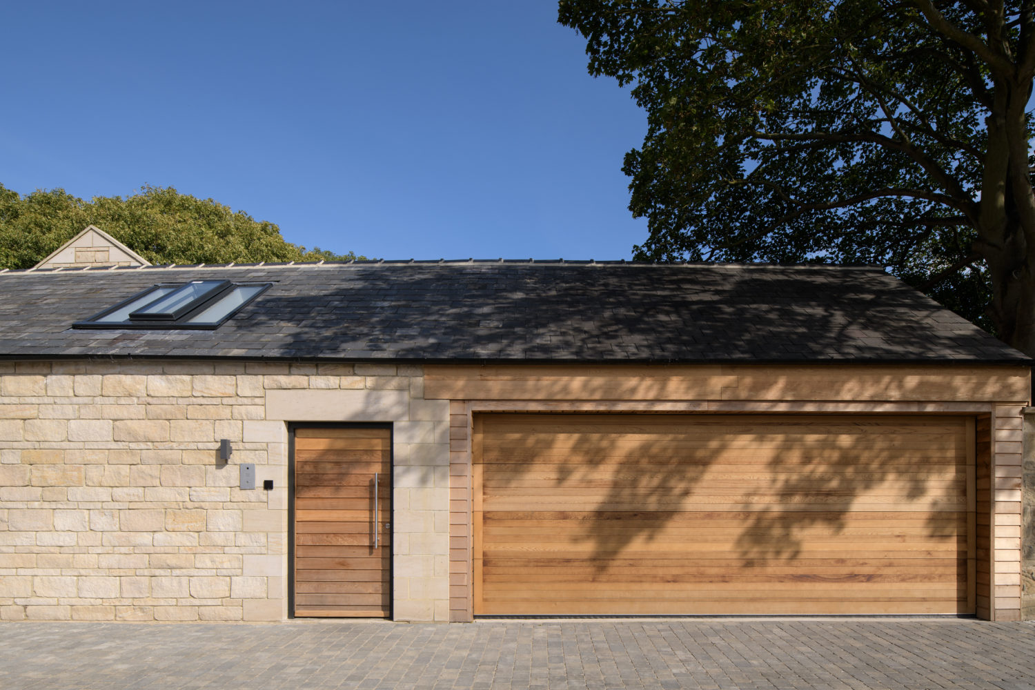 Close up stone built garage with a wood panelled door to the left of a matching garage door
