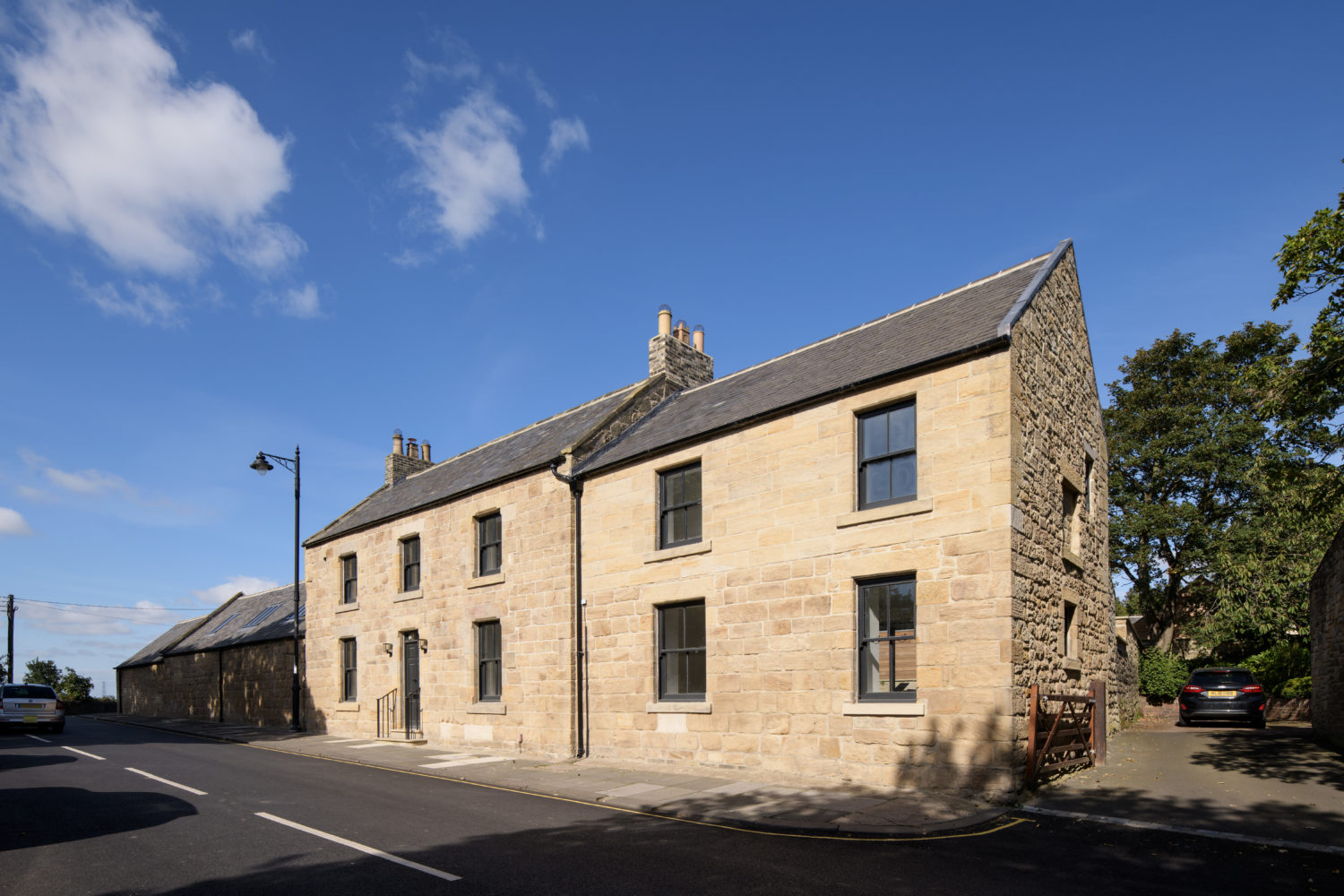 Exterior front of a two storey stone built house with blue sky above