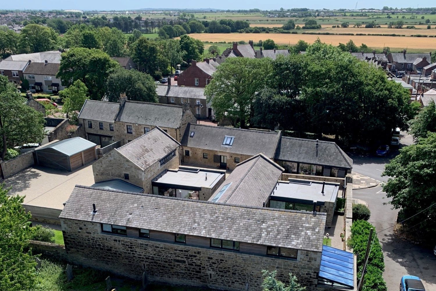 Drone view of connected stone buildings with countryside surrounding