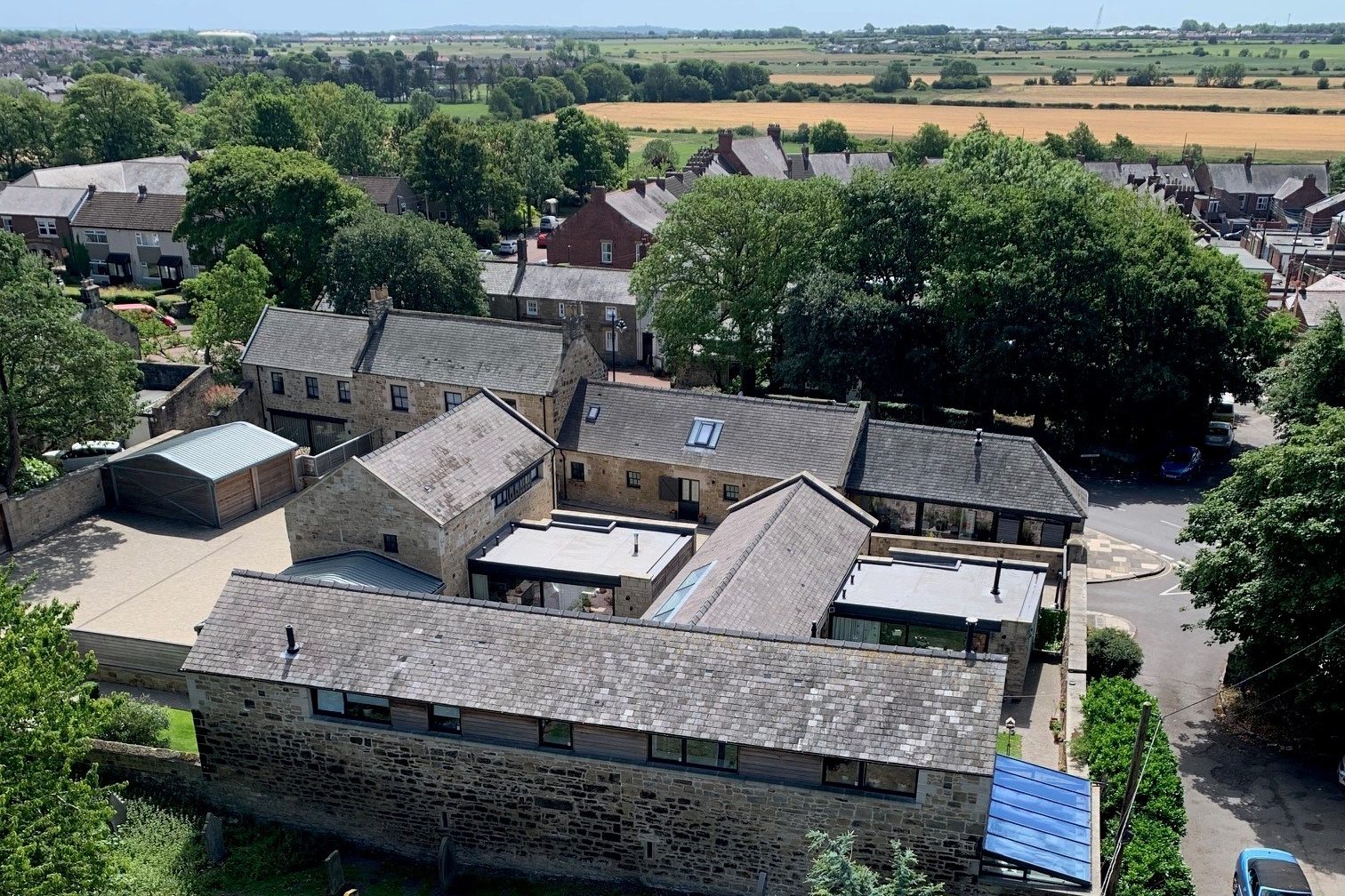 Drone view of connected stone buildings with countryside surrounding