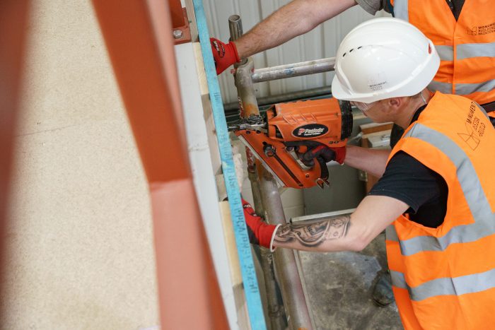 Construction worker in hi vis, using a drill.